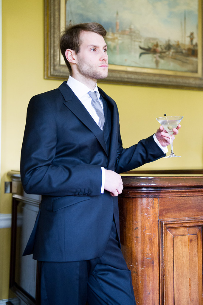 Groom wearing a blue suit with a drink