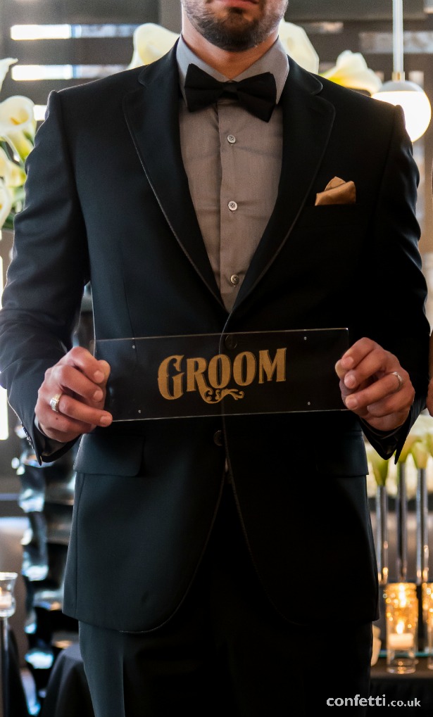 Groom in black Art Deco theme with sign