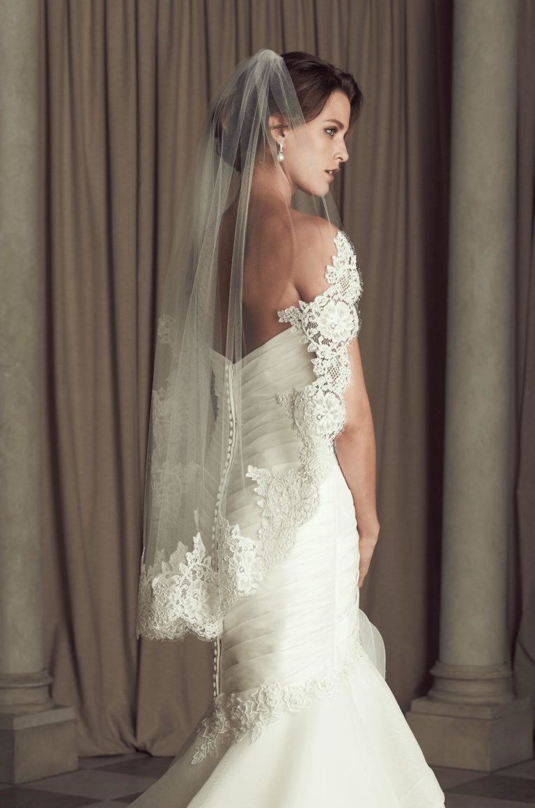 model posing in lace wedding dress and chapel length veil all by Paloma Blanca