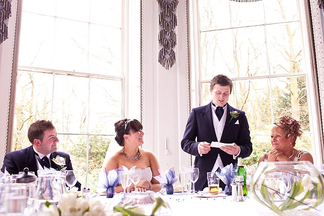 groom making speech while bride laughs