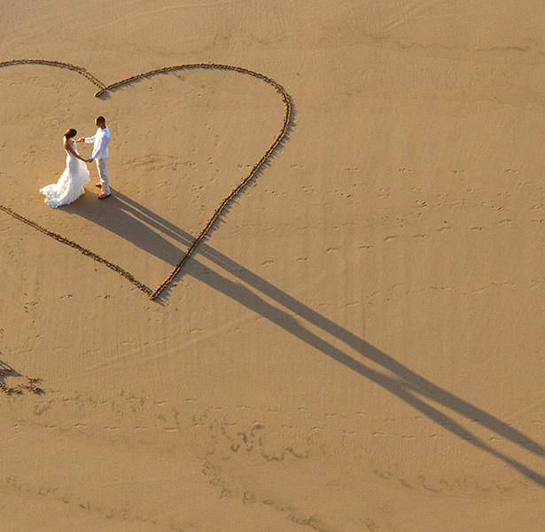 Bride and Groom's shadow and love heart in the sand