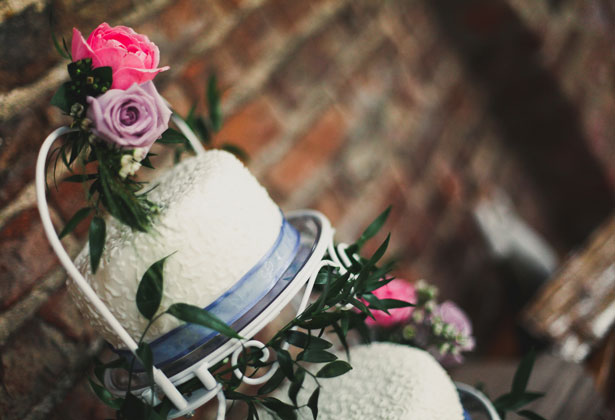 White wedding cake with blue ribbon and pink and lilac roses 