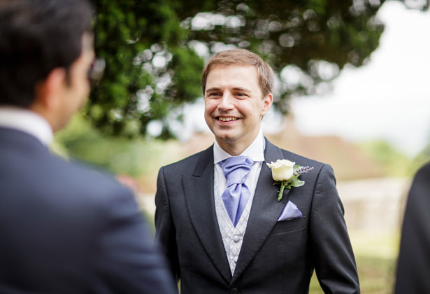 Groom in a Moss Bros suit waiting outside the church 