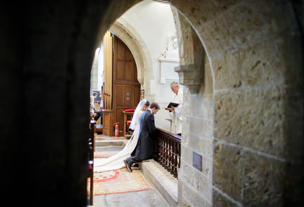 Bride and groom kneeling at the alter