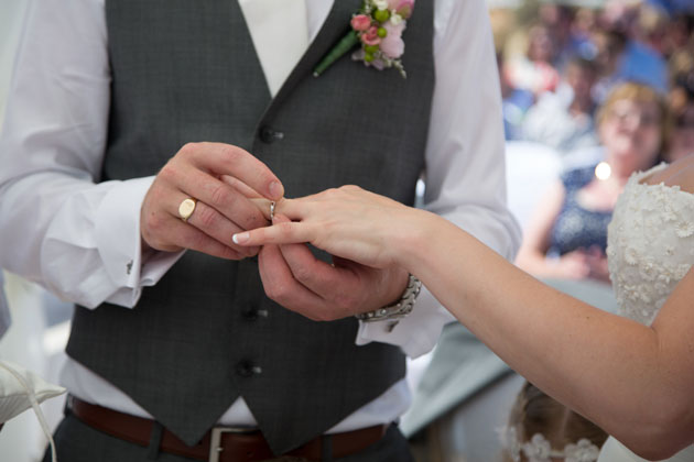 The groom placing the ring on the brides finger 