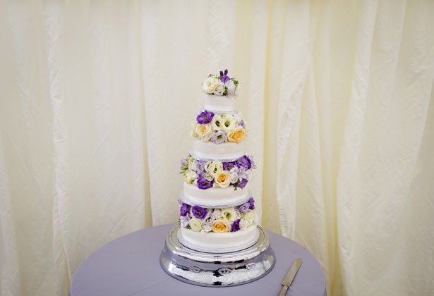 White wedding cake with purple, yellow and white flowers    