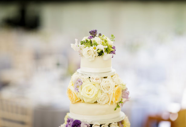 White wedding cake with purple, yellow and white flowers    