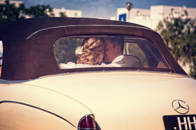 The bride and groom in a white vinatge wedding car 