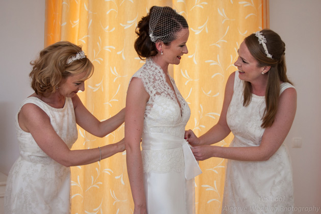 Bridesmaids helping the bride with the final touches to her dress 