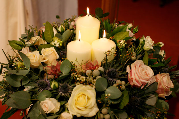 Winter inspired flower arrangement with roses, candles and thistles 