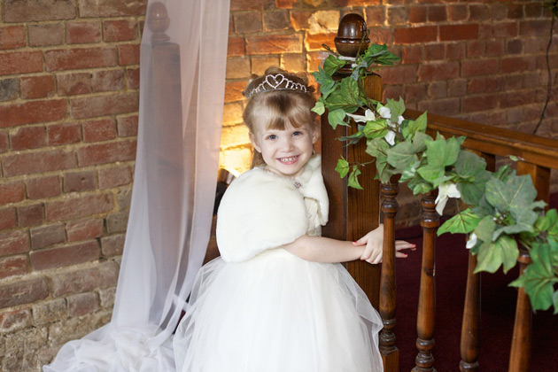 The flower girl in a white dress and tiara 