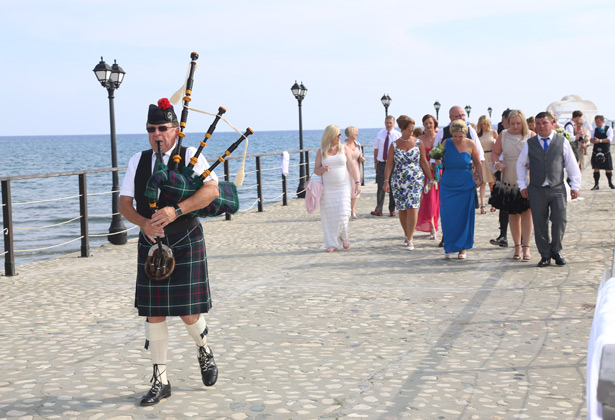 Traditional piper leading the wedding party to the reception 