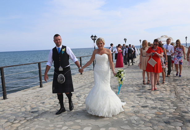 The bride and groom holding hands on the pier 