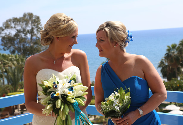 Bride with her bridesmaid in her blue off the shoulder dress by Dessy 