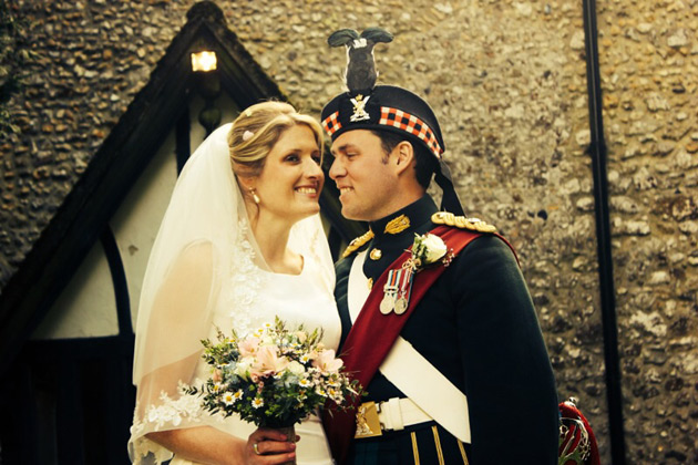 Bride in a lace wedding dress and veil with her groom in military uniform 