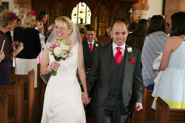 Smiling bride and groom exit the church after the ceremony | Confetti.co.uk