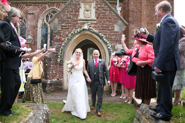 Wedding guests throwing confetti over the newlyweds after the church ceremony | Confetti.co.uk