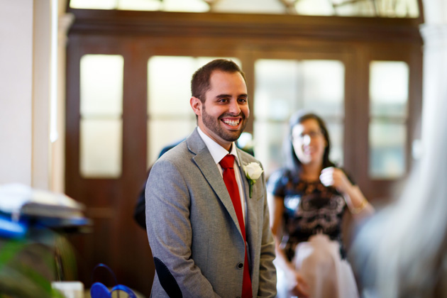 The groom waiting for the bride at the ceremony in a grey suit and red tie | Confetti.co.uk