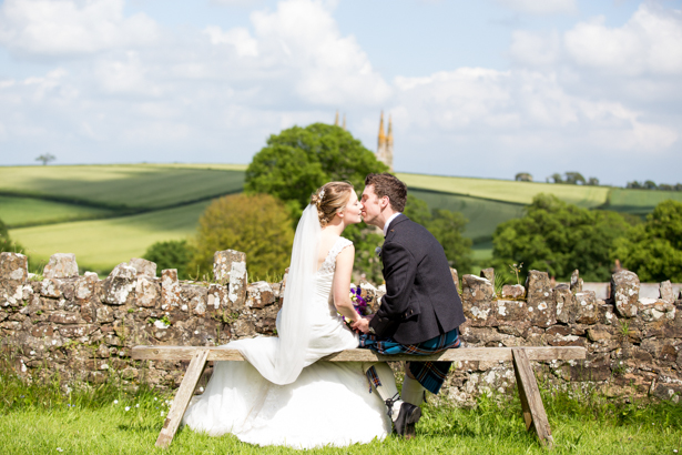 The newlyweds kissing on the bench | Confetti.co.uk