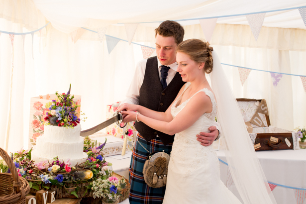 Bride and groom cutting their wedding cake with a sword | Confetti.co.uk