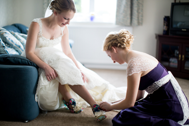 Bridesmaid helping the bride tie her shoe | Wedding moment | Confetti.co.uk