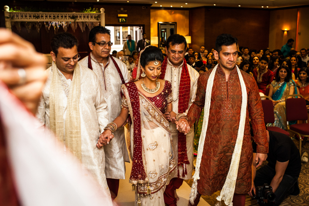 Bride walking down the aisle with her family| Confetti.co.uk