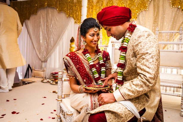 Bride and groom in the mandap enjoying the ceremony | Traditional Hindu wedding customs | Confetti.co.uk