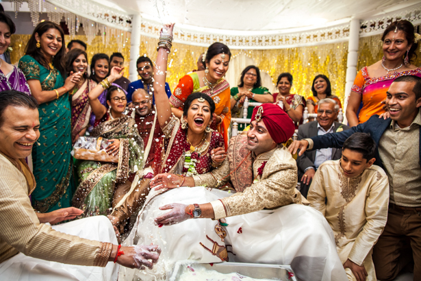 Bride and groom playing a traditional game of hiding their rings | Traditional Hindu wedding customs | Confetti.co.uk