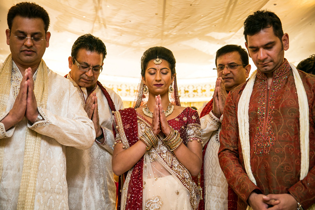 Bride with her family in a traditional Indian bridal outfit praying | Hindu wedding ceremony | Confetti.co.uk