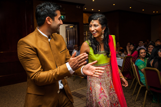 The bride in her traditional Indian outfit and the groom in a brown suit by Zara entering their Indian Reception | Indian wedding reception ideas| Confetti.co.uk