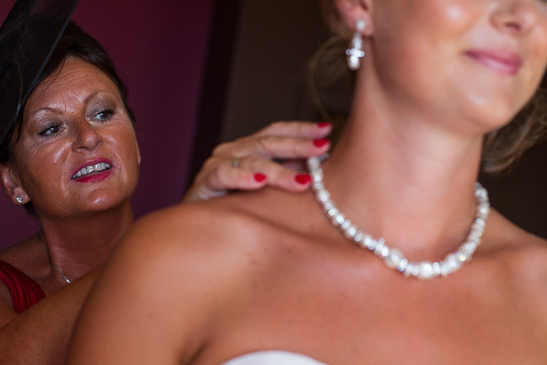 Mother of the Bride Wedding Duties | Image courtesy of Yes I do! Algarve Wedding Photography|Bride putting the brides pearl necklace on for her | Mother of the bride and bride moments | Confetti.co.uk