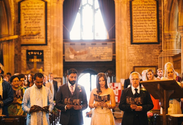 The bride and groom together at the altar singing hymns | Francesca & Arun's Fusion Real Wedding | Confetti.co.uk  