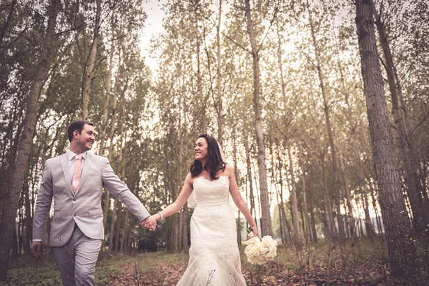 Official wedding shot in the forest | Bride and groom holding hands in the forest | Morgan and James Real Wedding By Infinity Weddings | Confetti.co.uk