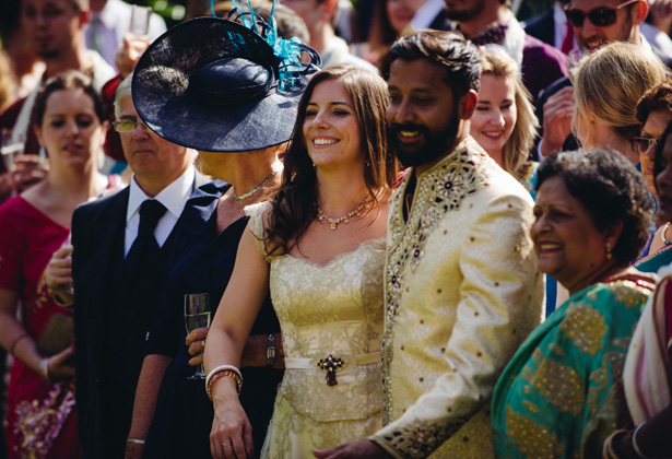 Bride and groom in their gold wedding attire with their wedding guests | Francesca & Arun's Fusion Real Wedding | Confetti.co.uk  