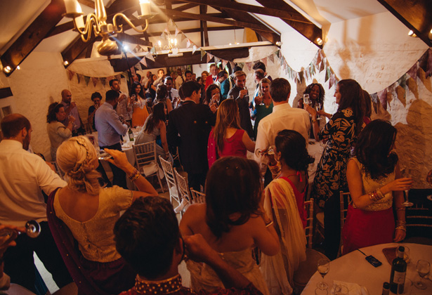 Wedding guests on their feet toasting the newlyweds | Francesca & Arun's Fusion Real Wedding | Confetti.co.uk  