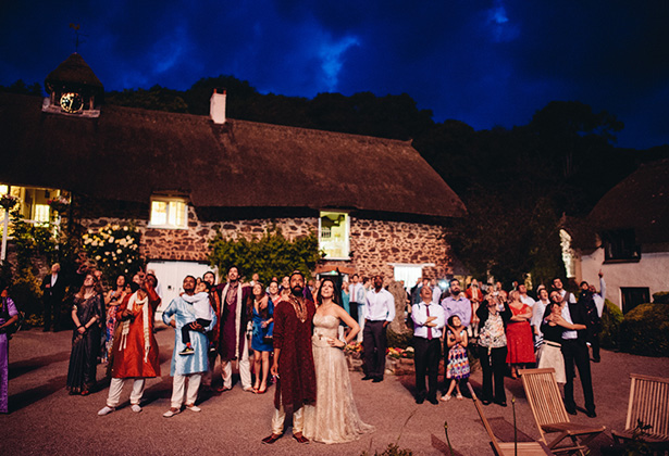 The newlyweds and the wedding guests enjoying the fireworks display at the end of the night | Francesca & Arun's Fusion Real Wedding | Confetti.co.uk  