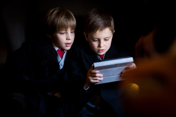 Page boys playing on their Ipad | Abigail and Chris's Real Christmas Wedding | Confetti.co.uk 