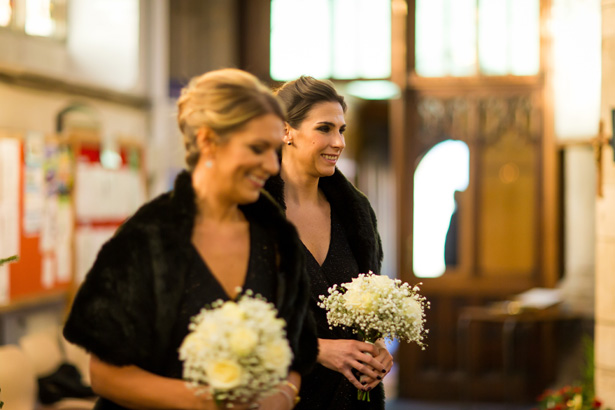 Bridesmaids in black dresses walking down the aisle | Abigail and Chris's Real Christmas Wedding | Confetti.co.uk 