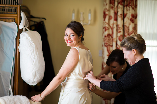 Bridesmaids helping the bride with her dress | Abigail and Chris's Real Christmas Wedding | Confetti.co.uk 