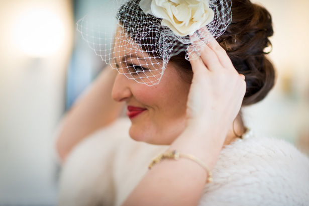 Bride putting the final touches to her attire | White bridal fascinator | Abigail and Chris's Real Christmas Wedding | Confetti.co.uk 