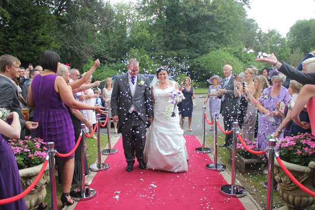 Guests throwing confetti over the newlyweds| Purple themed wedding| Rhiannon & Michael's Real Wedding | Confetti.co.uk