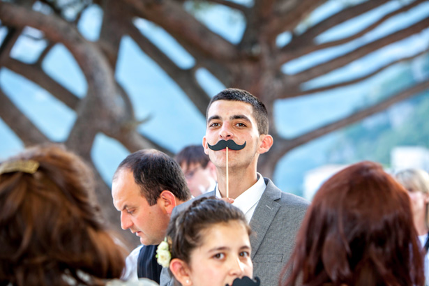 Wedding reception at Villa Maria, Italy Wedding guest holding a comedy moustache| Funny wedding moments to capture | Leanne and Chris's Real Italian Wedding | Confetti.co.uk