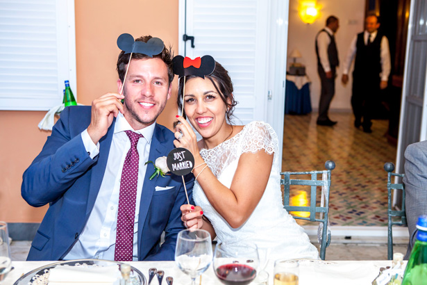 Wedding reception at Villa Maria, Italy | Bride and groom holding comedy Mickey and Minnie mouse props | Leanne and Chris's Real Italian Wedding | Confetti.co.uk