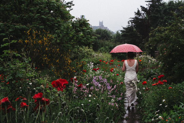 The bride walking through the garden with an umbrella| Vintage wedding ideas | Steph and Gary's Real Garden Wedding | Confetti.co.uk 