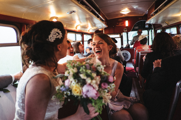 The bride and the bridesmaid enjoying the drive to the reception in the vintage red London bus | Fun wedding ideas | Steph and Gary's Real Garden Wedding | Confetti.co.uk 