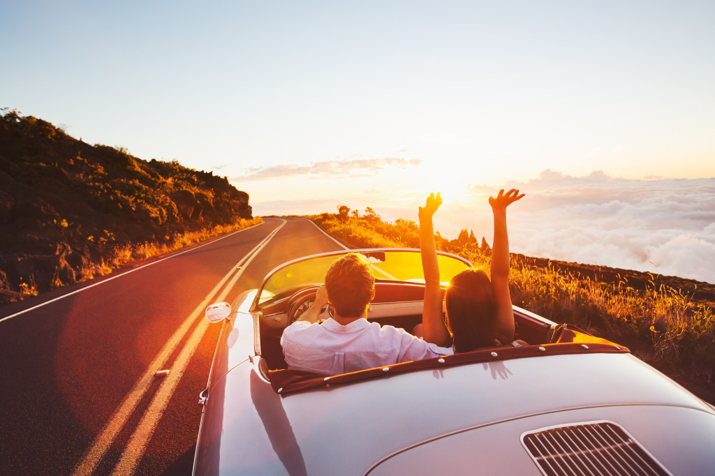 Honeymooners driving towards a beautiful sunset