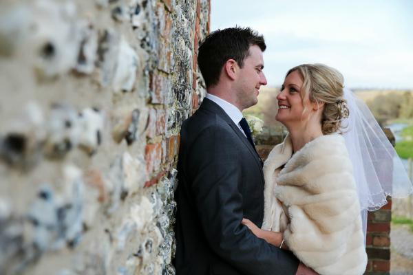 Bride and Groom Stare Lovingly Against an Exposed Brick Wall | Confetti.co.uk