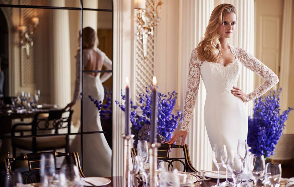 Lady posing in her dressing room in her ivory mermaid style Caroline Castigliano dress with sweetheart neck