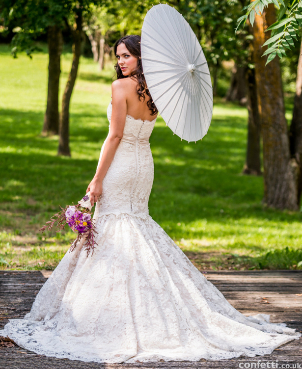 Girl posing with beautiful wedding gown and flowers and stunning parasol from the Confetti Shop