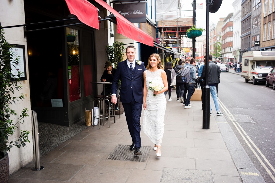 Bride & Groom walking through Soho in London City on their Wedding day | Confetti.co.uk